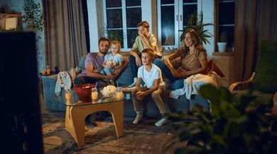 Famille réunie sur le canapé devant les chaînes de TV en direct, le soir