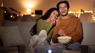 Couple qui partage du pop-corn devant un nouveau film à la maison, sur un projecteur