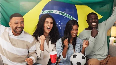 Amis avec un ballon de foot qui célèbrent un match en direct à la TV, drapeau à la main