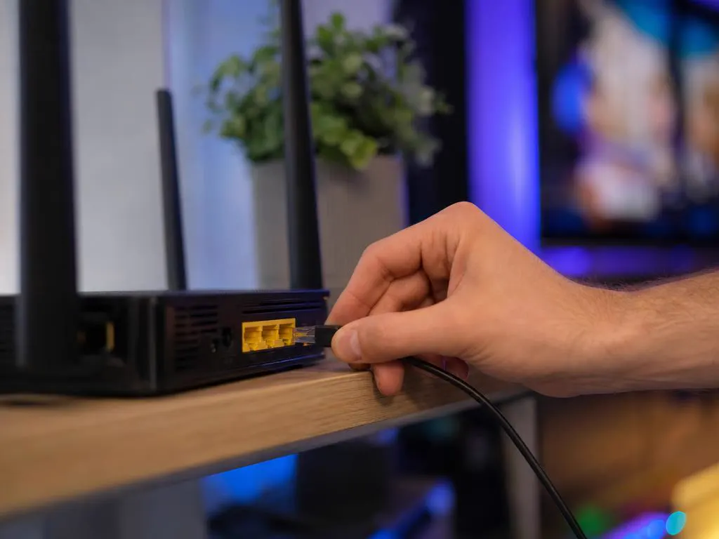 Main qui débranche le câble d’alimentation d’une box Wi-Fi