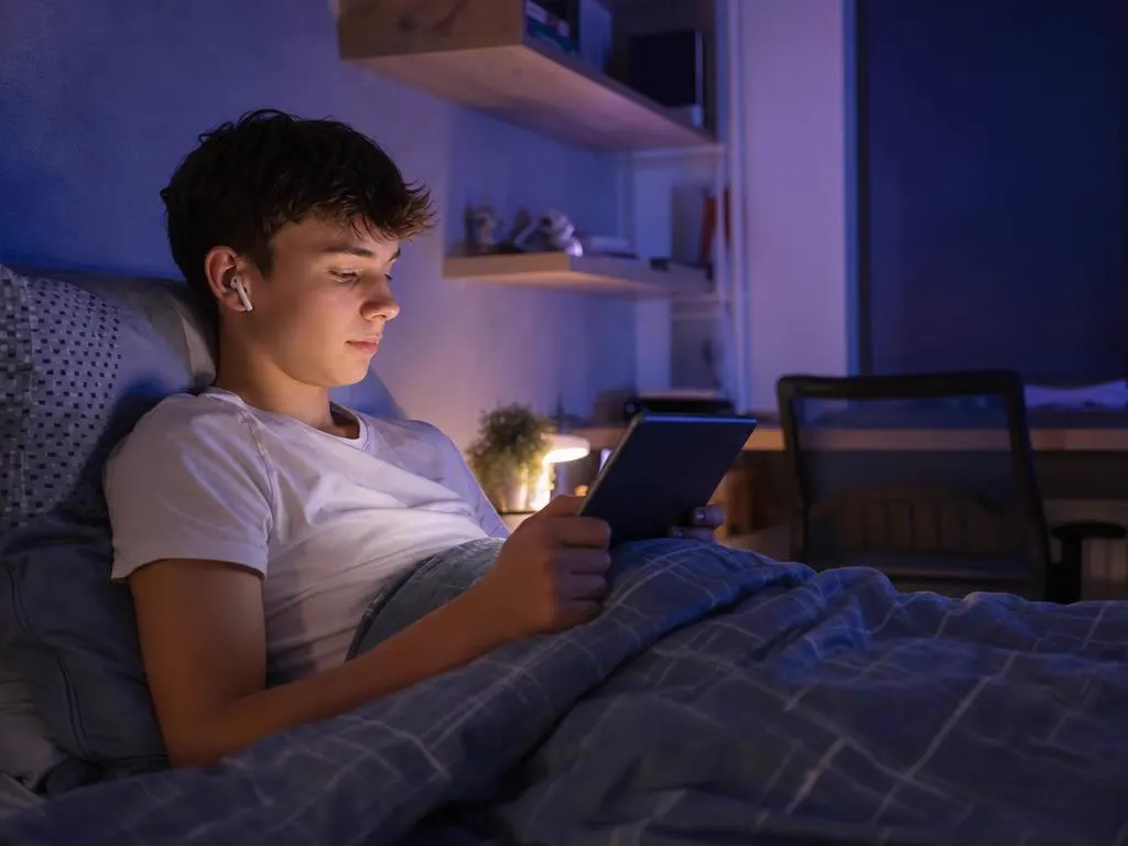 Adolescente qui regarde une série sur une tablette Android au lit