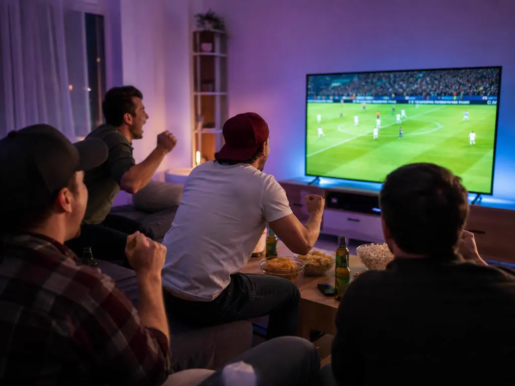 Amis qui encouragent une équipe de football en regardant l’IPTV Hisense
