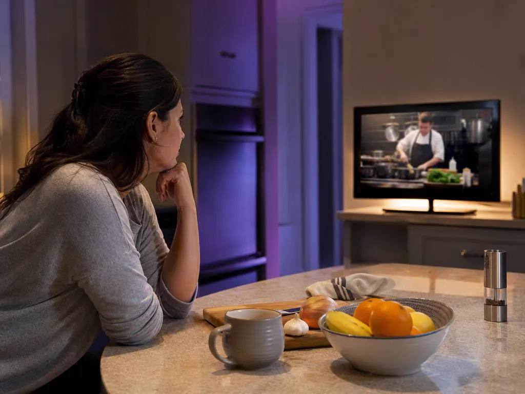 Woman watching a cooking show on a kitchen TV
