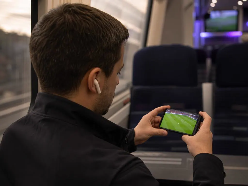 Commuter watching a live match on a phone on the train