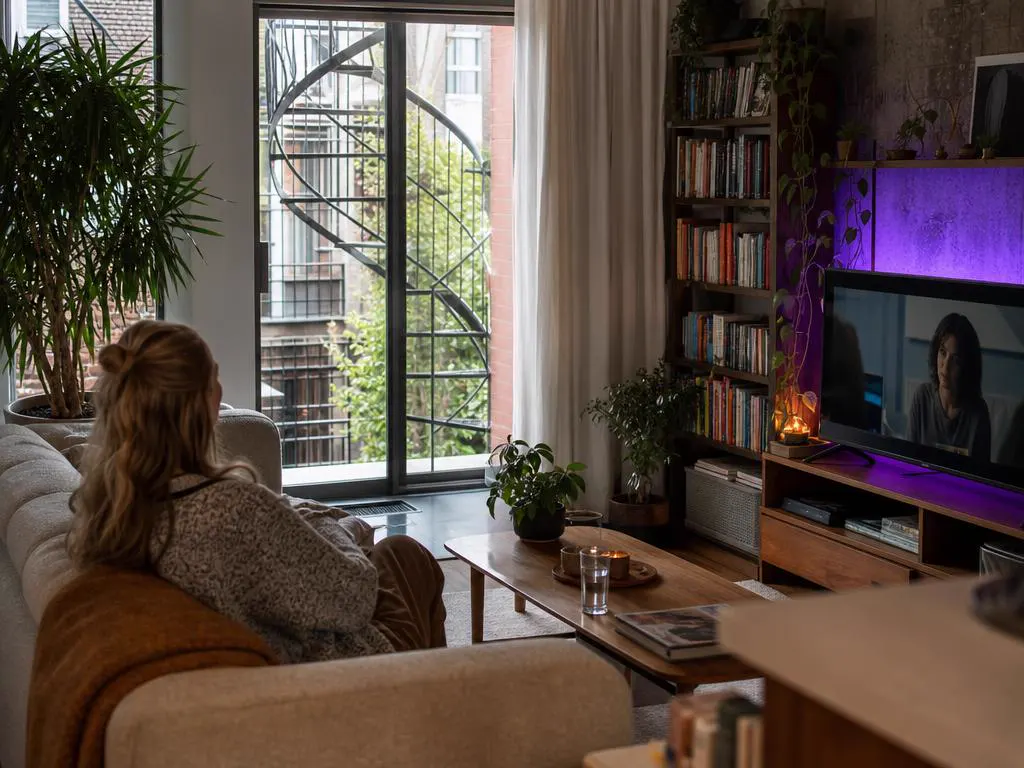 Bright Montreal triplex apartment with a spiral staircase visible outside and a TV playing a French drama