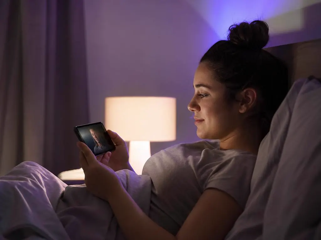 Woman watching a series on a phone in bed