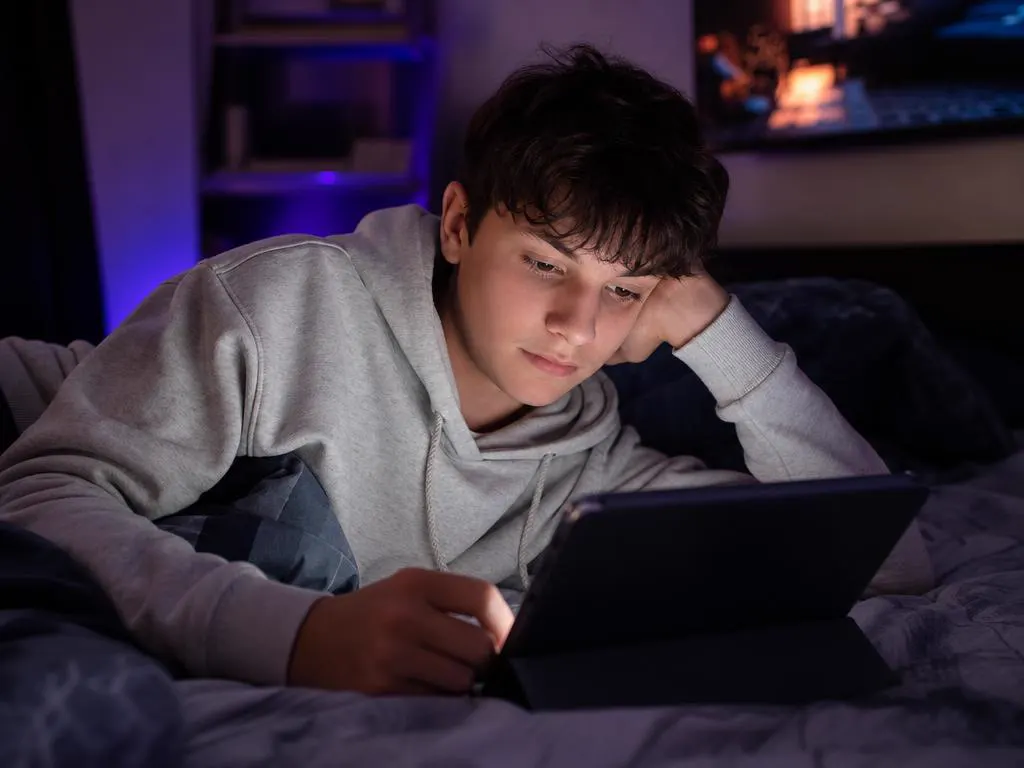 Teenager watching a movie on a tablet in bed