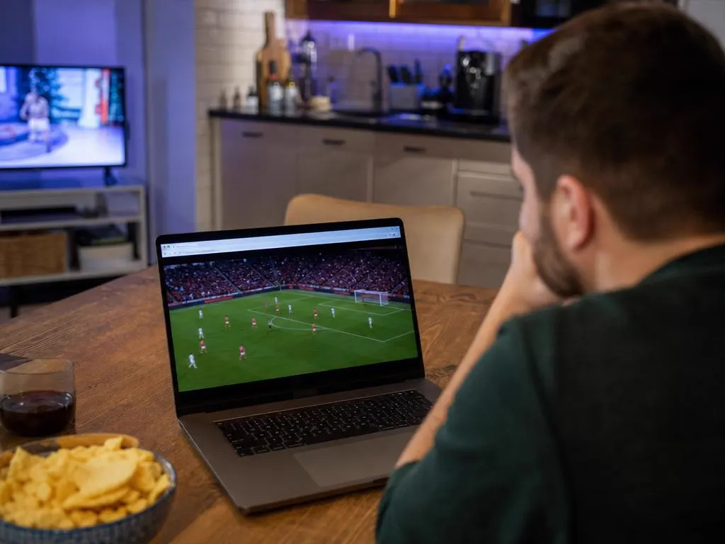 Laptop on a kitchen table playing a live sports channel in a browser window