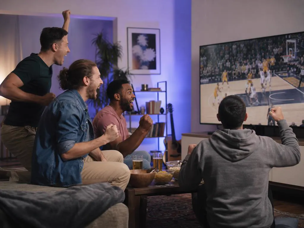 Friends cheering a live game on a big TV