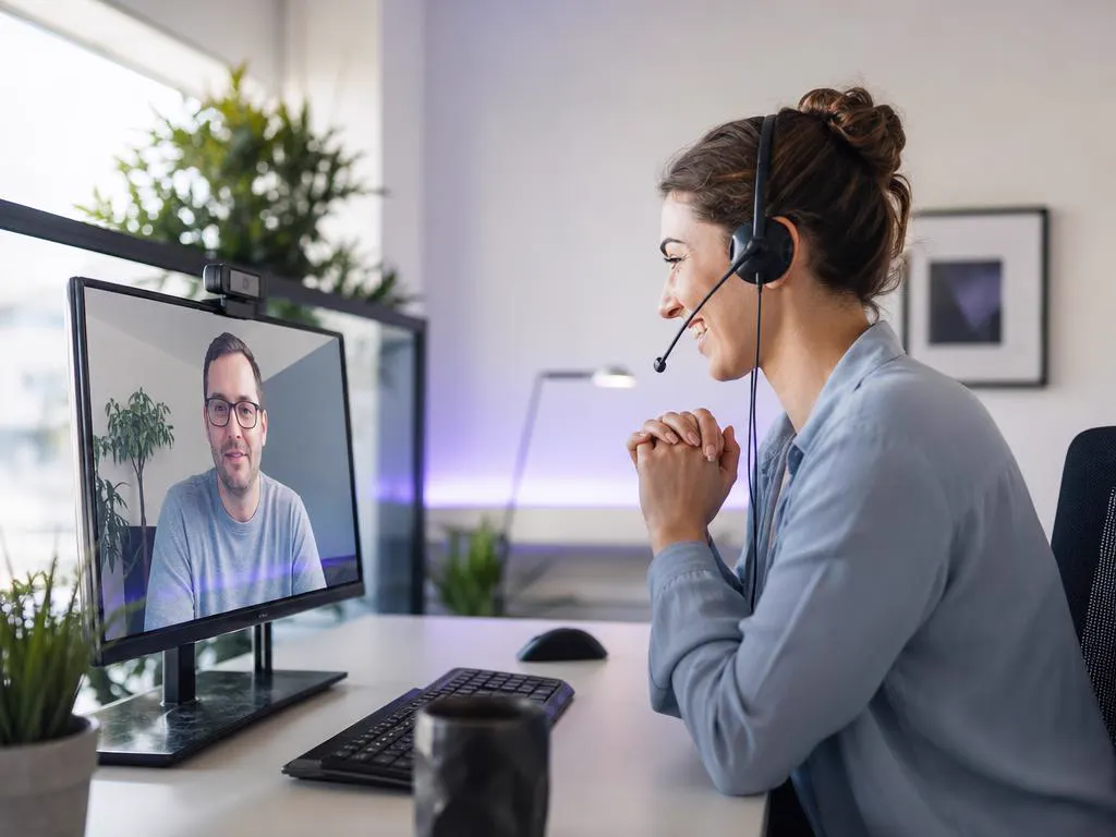 Smiling support agent with a headset helping a customer on a video call