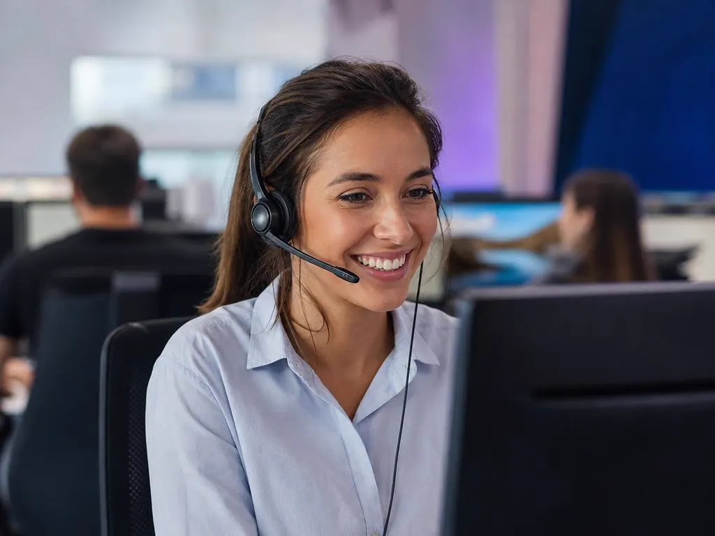 Smiling support agent with a headset helping a customer by phone