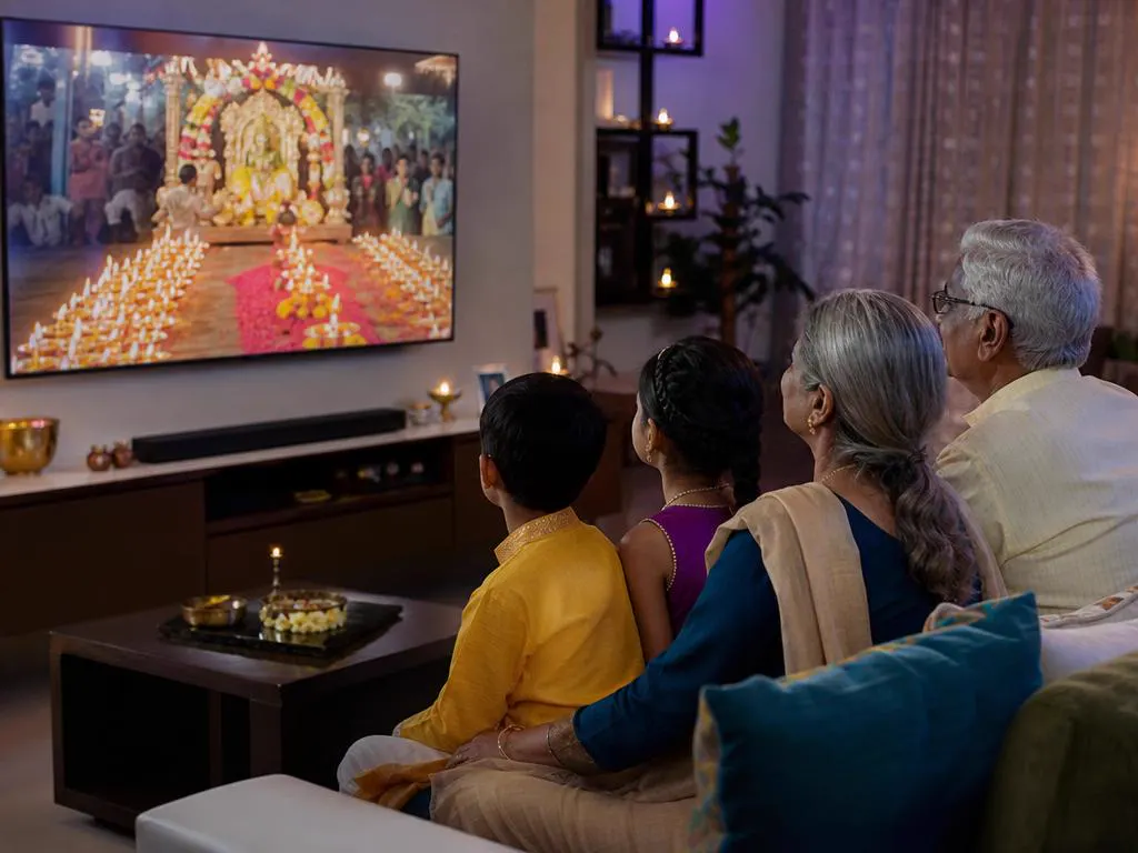 Grands-parents et petits-enfants tamouls devant la retransmission d’une fête religieuse à la TV