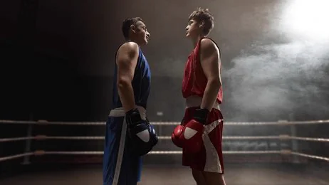 Deux boxeurs face à face sur le ring sous les projecteurs avant un combat en direct
