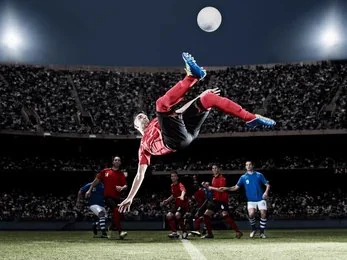 Footballeur qui marque d’un retourné acrobatique dans un stade illuminé pendant un match en direct